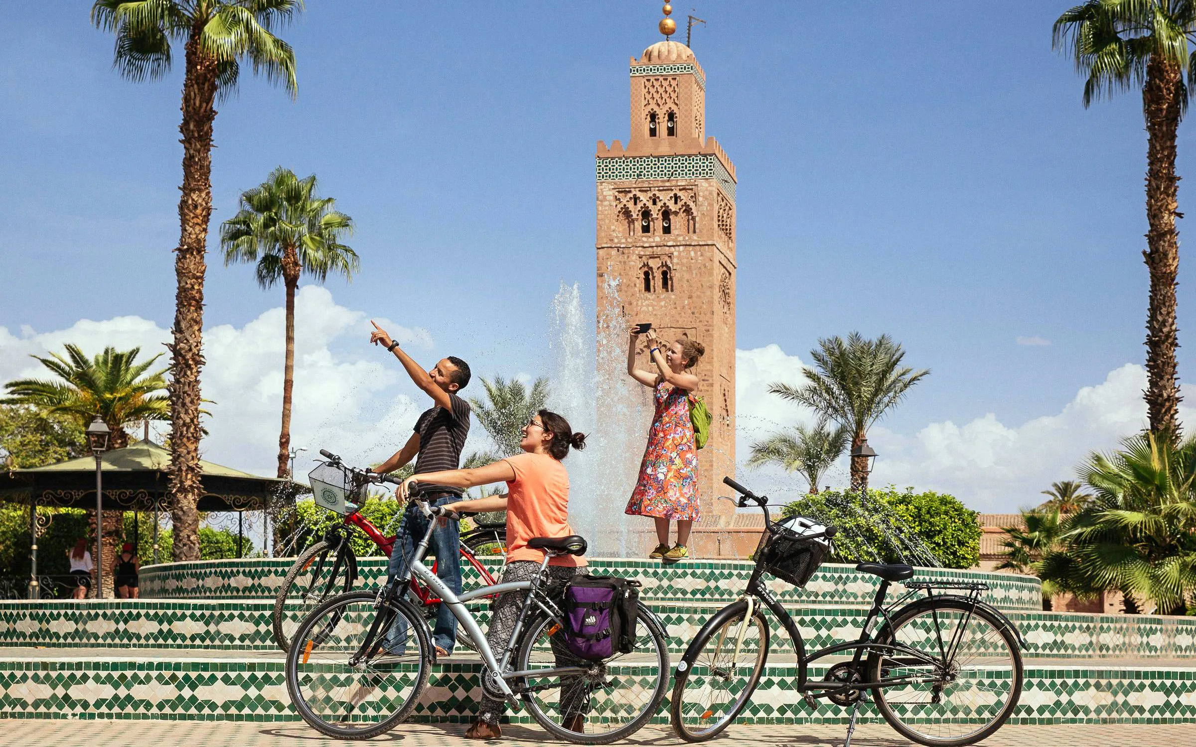 Cyclists at Koutoubia Mosque fountain during Marrakech city bike tour.