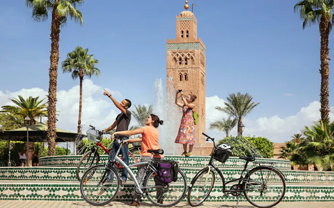 Cyclists at Koutoubia Mosque fountain during Marrakech city bike tour.