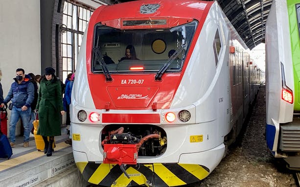 Malpensa Express train at platform with passengers boarding in Milan, Italy.