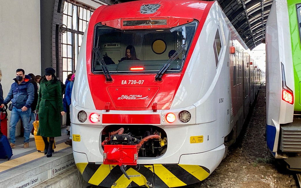 Malpensa Express train at Milan Cadorna Station platform with passengers nearby.