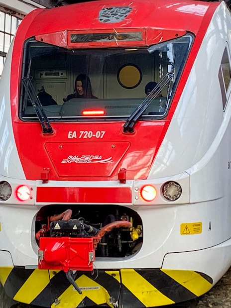 Malpensa Express train at Milan Cadorna Station platform with passengers nearby.