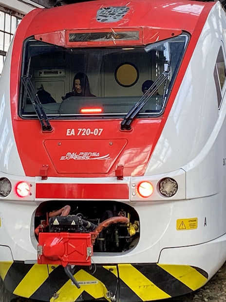 Malpensa Express train at Milan Cadorna Station platform with passengers nearby.