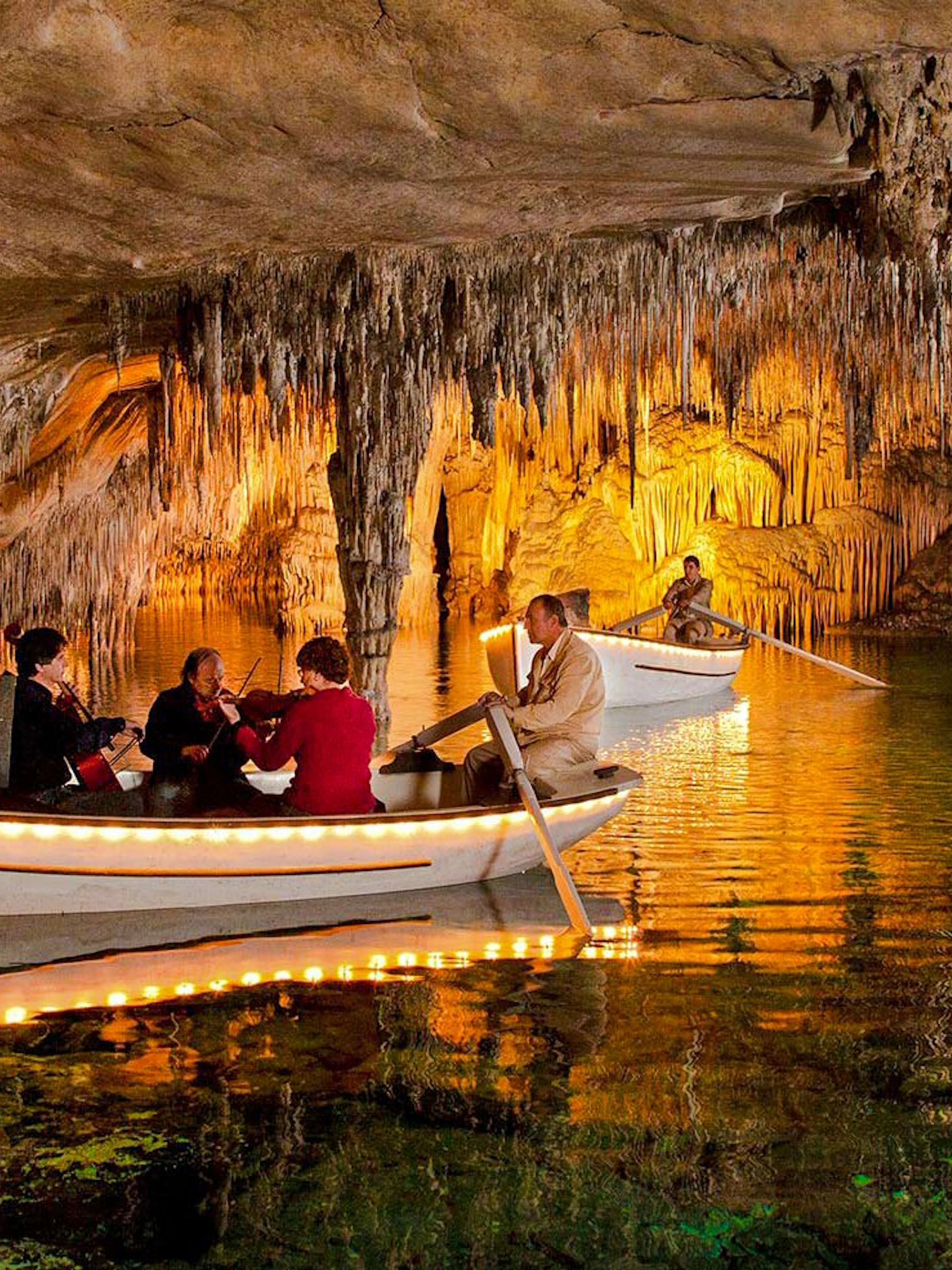 Boat tour with musicians inside Drach Caves, Mallorca, surrounded by stalactites.