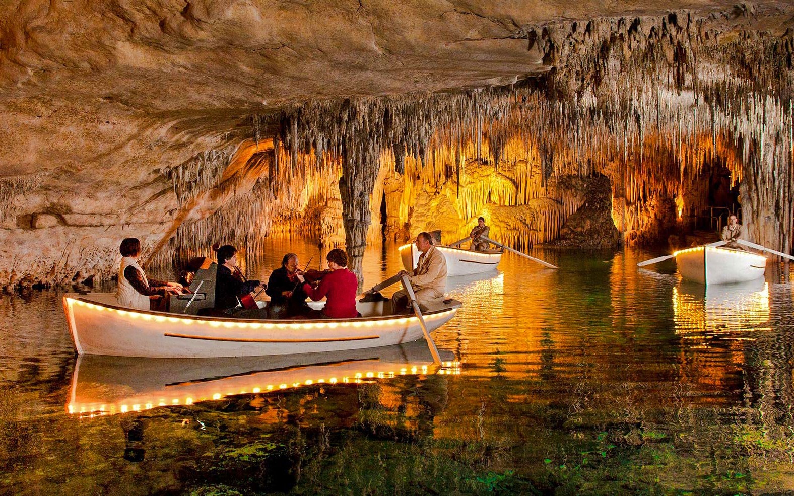 Boat tour with musicians inside Drach Caves, Mallorca, surrounded by stalactites.