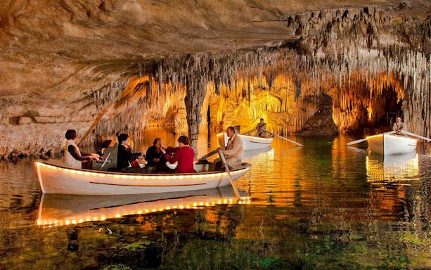 Boat tour with musicians inside Drach Caves, Mallorca, surrounded by stalactites.