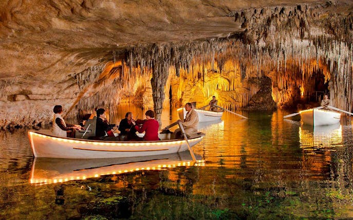Boat tour with musicians inside Drach Caves, Mallorca, surrounded by stalactites.