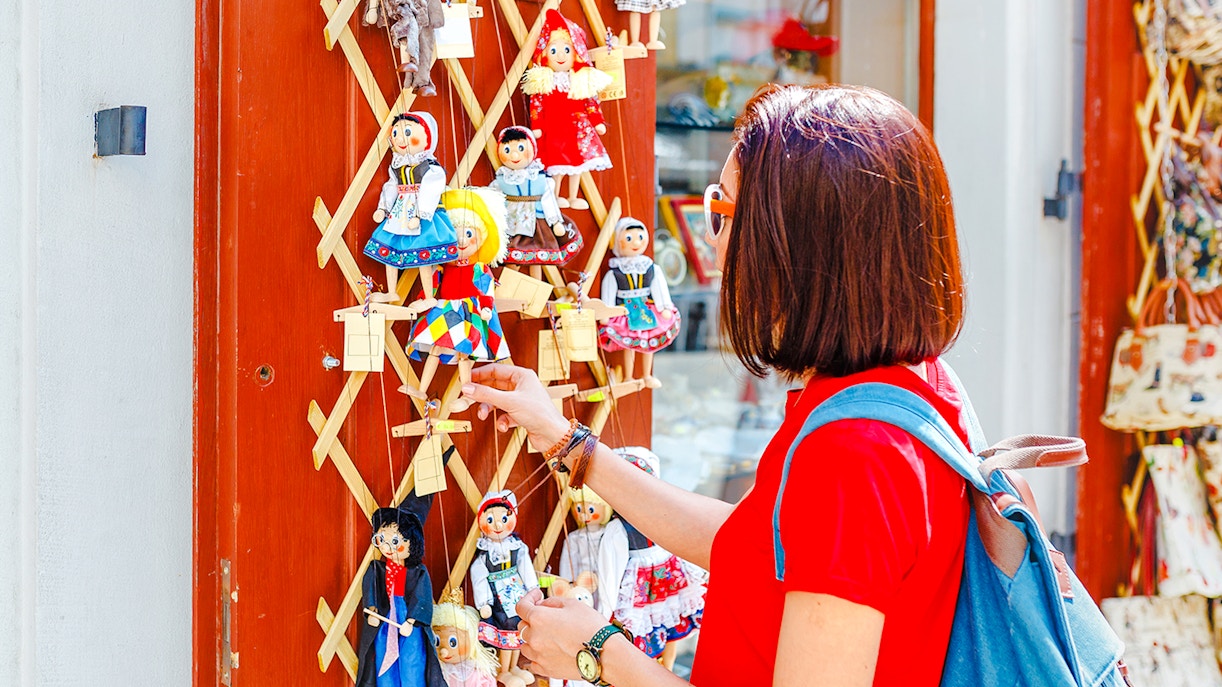 Woman examining traditional puppets on display in Austria.