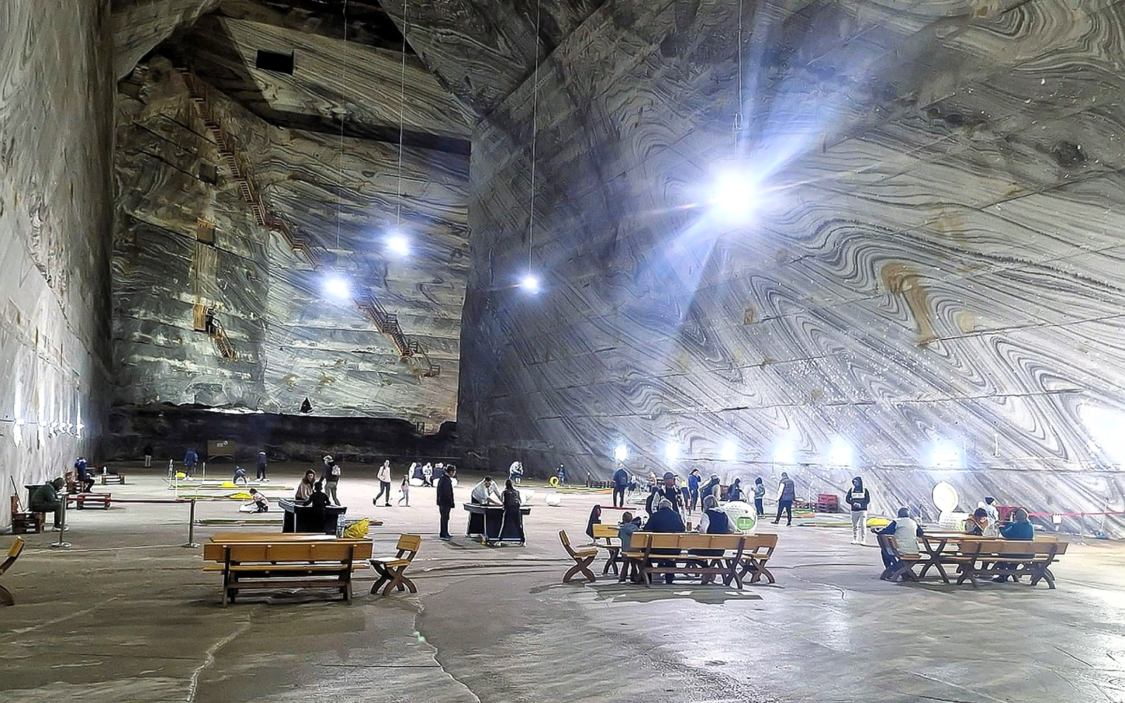 Guests exploring the vast interior of Slanic Salt Mine with illuminated walls.
