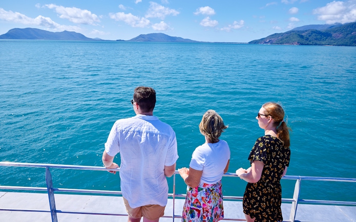 Tourists on a boat enjoying views of Fitzroy and Green Islands, Australia.