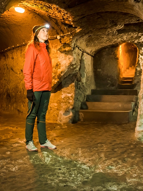 Guest exploring Kaymaklı Underground City in Cappadocia, standing in a dimly lit tunnel.