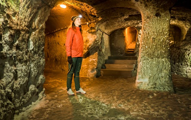 Guest exploring Kaymaklı Underground City in Cappadocia, standing in a dimly lit tunnel.