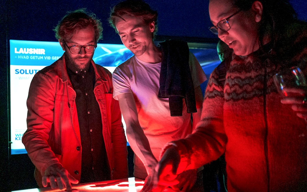 People interacting with a digital display on a Northern Lights cruise from Reykjavik.