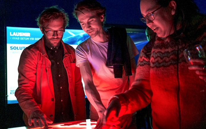 People interacting with a digital display on a Northern Lights cruise from Reykjavik.