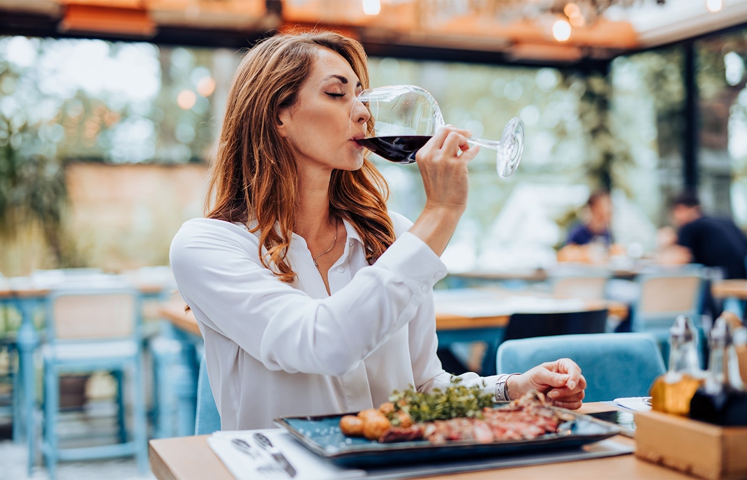 Woman dining at a modern Parisian restaurant, savoring French cuisine.