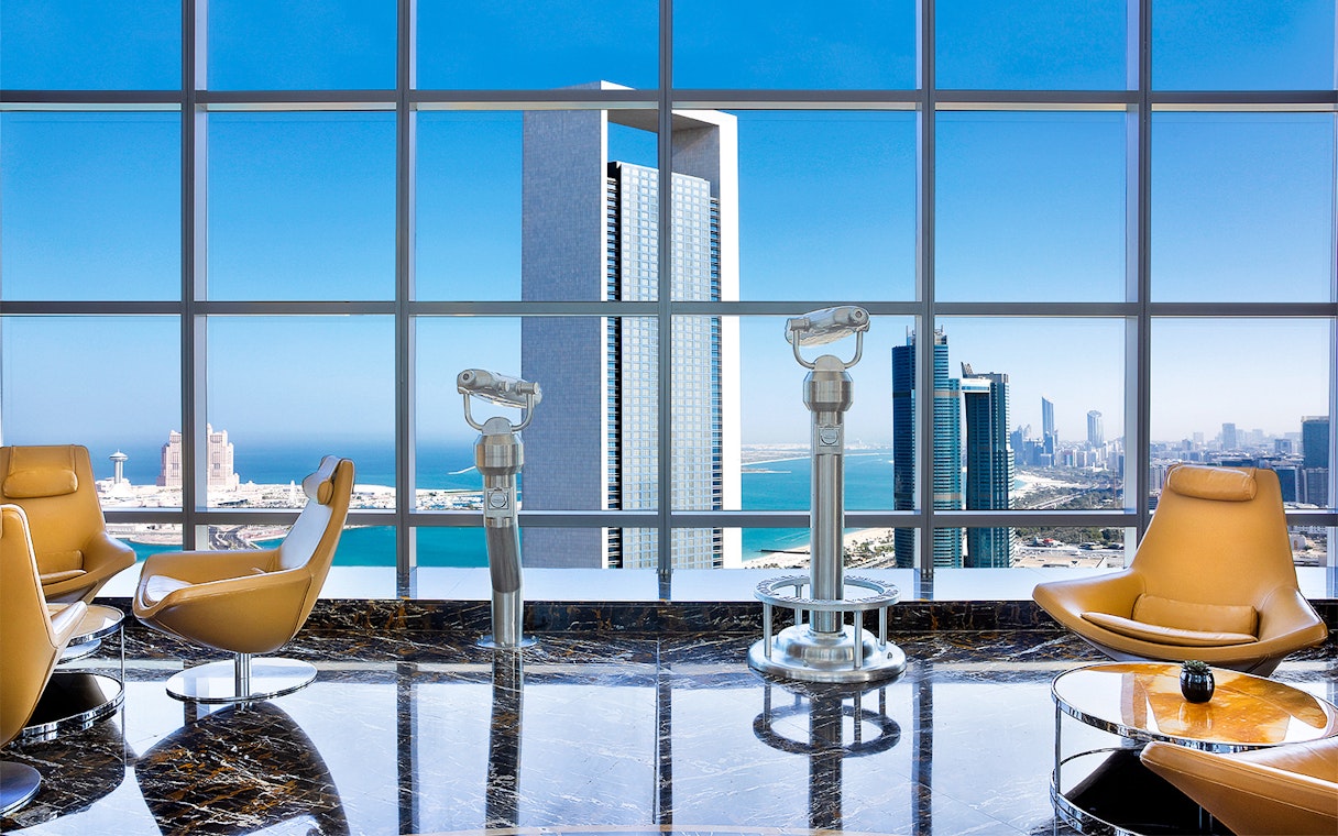 Observation deck view from 300 Etihad Tower, Abu Dhabi, with city skyline and telescopes.