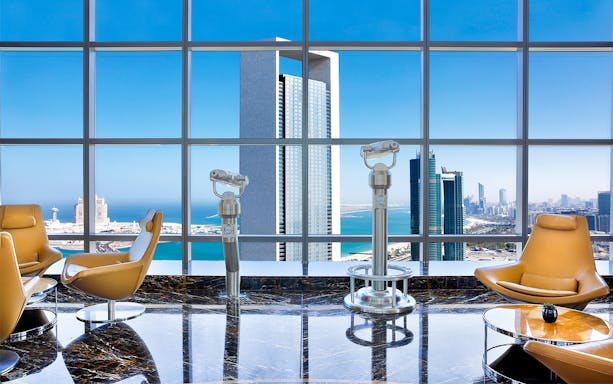 Observation deck view from 300 Etihad Tower, Abu Dhabi, with city skyline and telescopes.