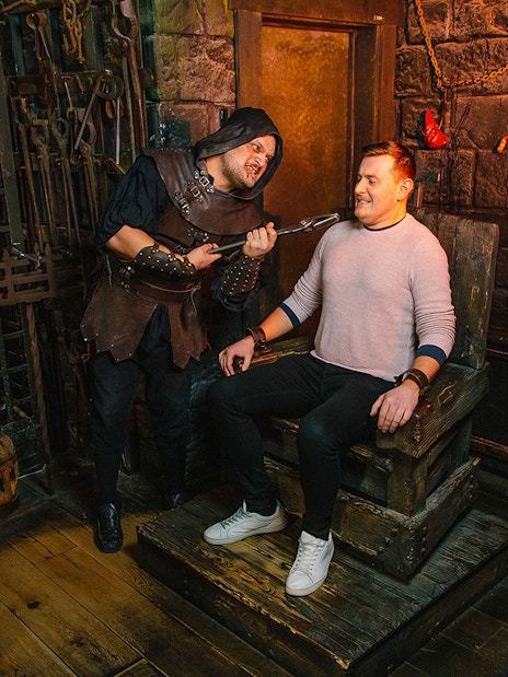 Medieval dungeon tour with actor in costume interacting with visitors.