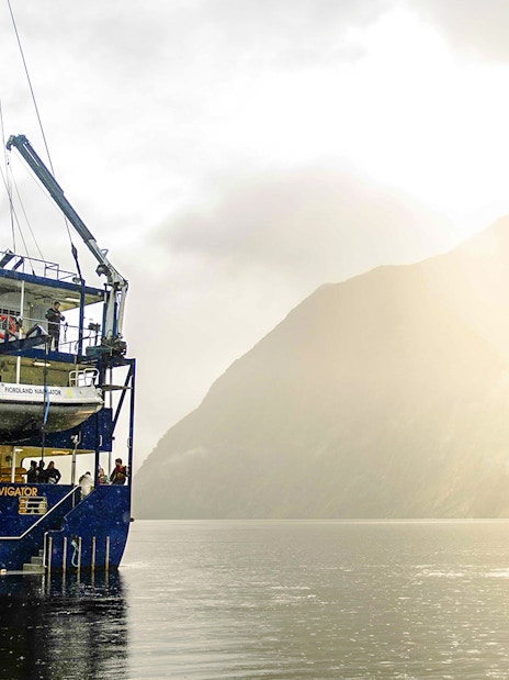 Kayaker paddling near a cruise ship in Doubtful Sound, New Zealand.