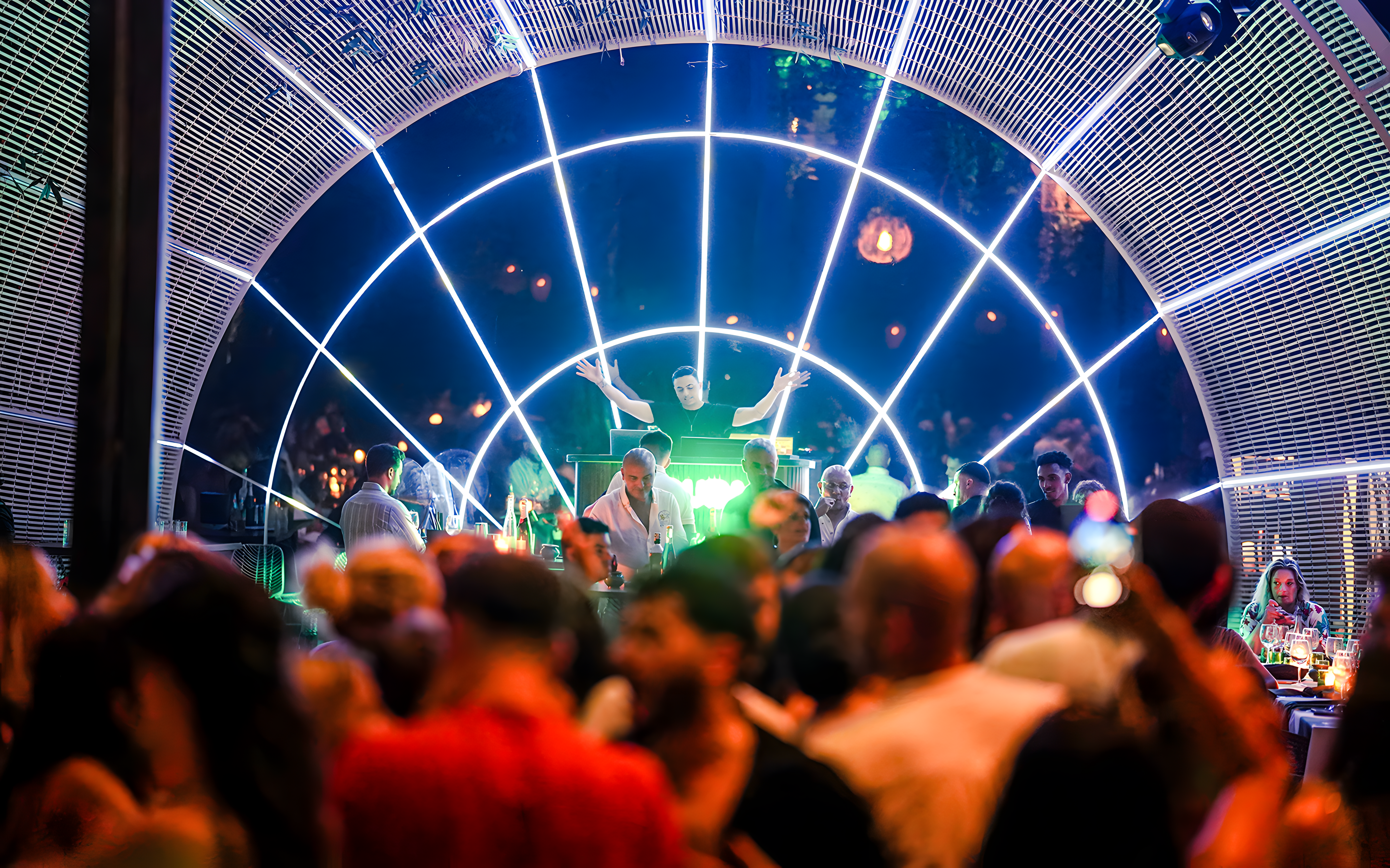 Performer on stage at Nouba Restaurant Dinner Show with vibrant lights and audience.