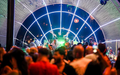 Performer on stage at Nouba Restaurant Dinner Show with vibrant lights and audience.