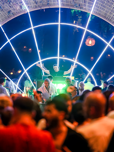 Performer on stage at Nouba Restaurant Dinner Show with vibrant lights and audience.