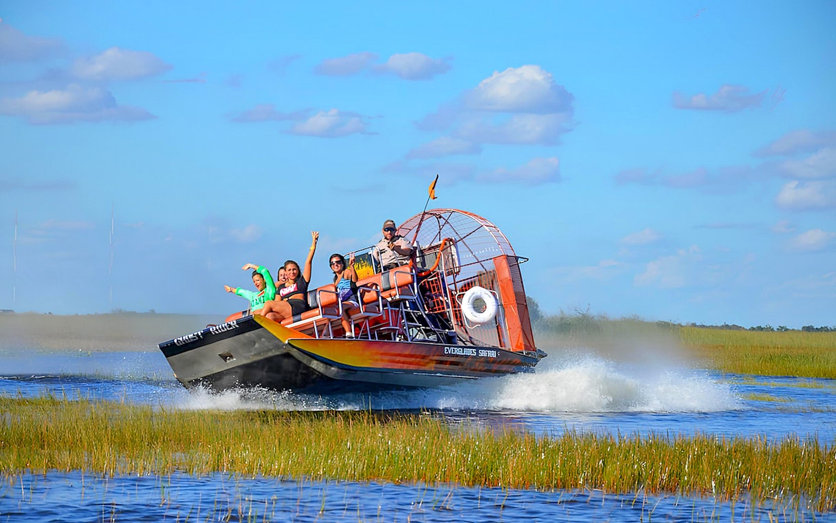 Airboat tour in Everglades Safari Park with passengers enjoying the ride, Miami.