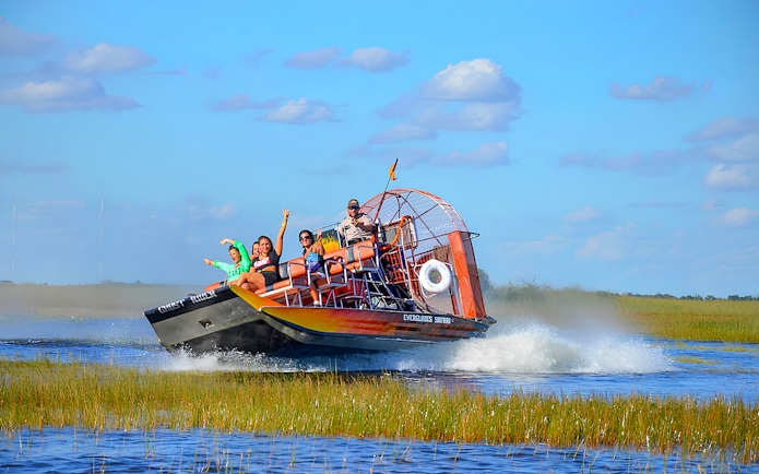 Airboat tour in Everglades Safari Park with passengers enjoying the ride, Miami.