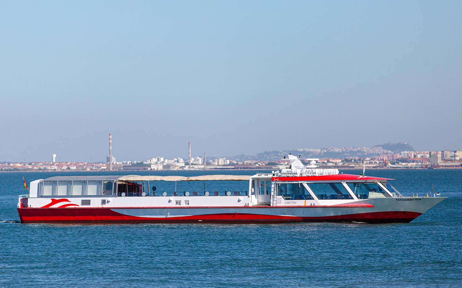 Boat cruising on Tagus River with Lisbon skyline in the background.