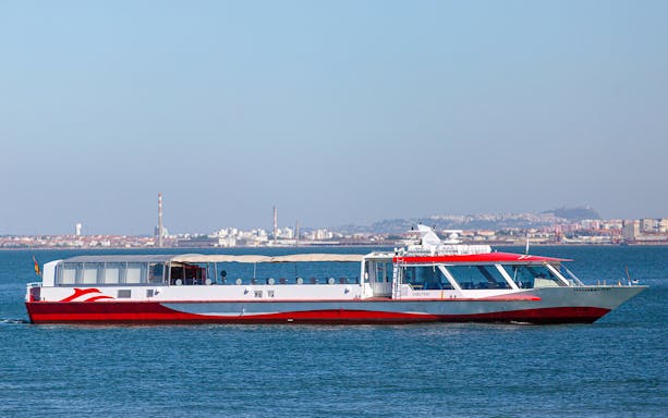 Boat cruising on Tagus River with Lisbon skyline in the background.