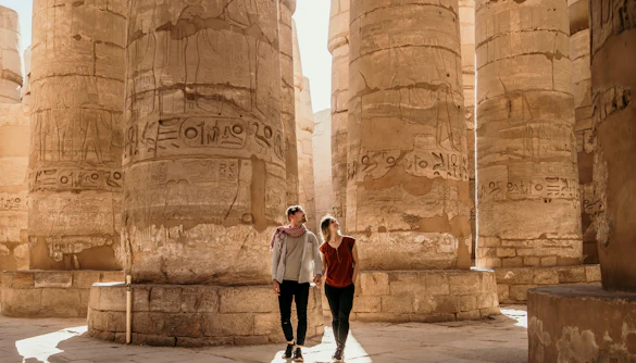 Couple exploring ancient columns at Luxor Temple, Egypt.