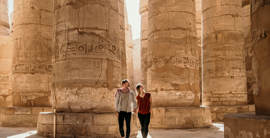 Couple exploring ancient columns at Luxor Temple, Egypt.