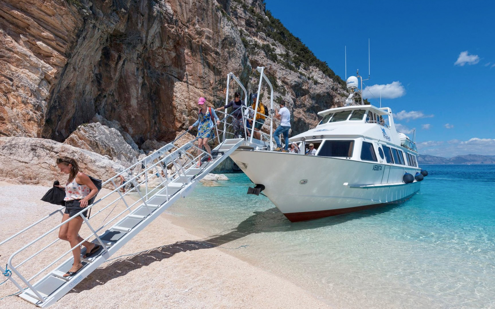 Visitors disembarking from a boat onto the beach at Gulf of Orosei, Italy.