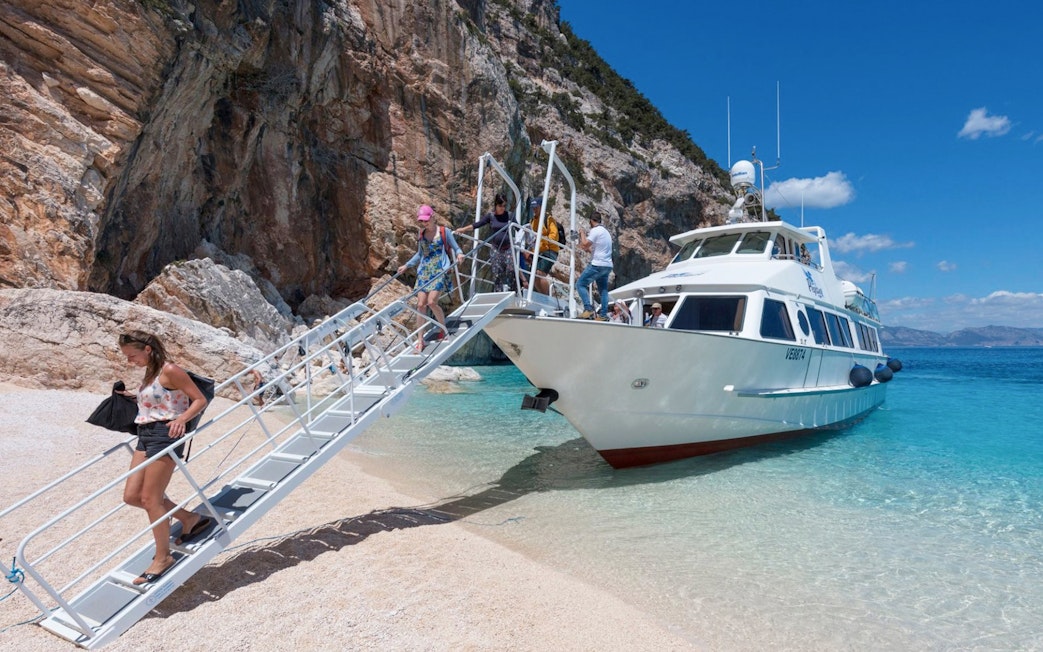 Visitors disembarking from a boat onto the beach at Gulf of Orosei, Italy.