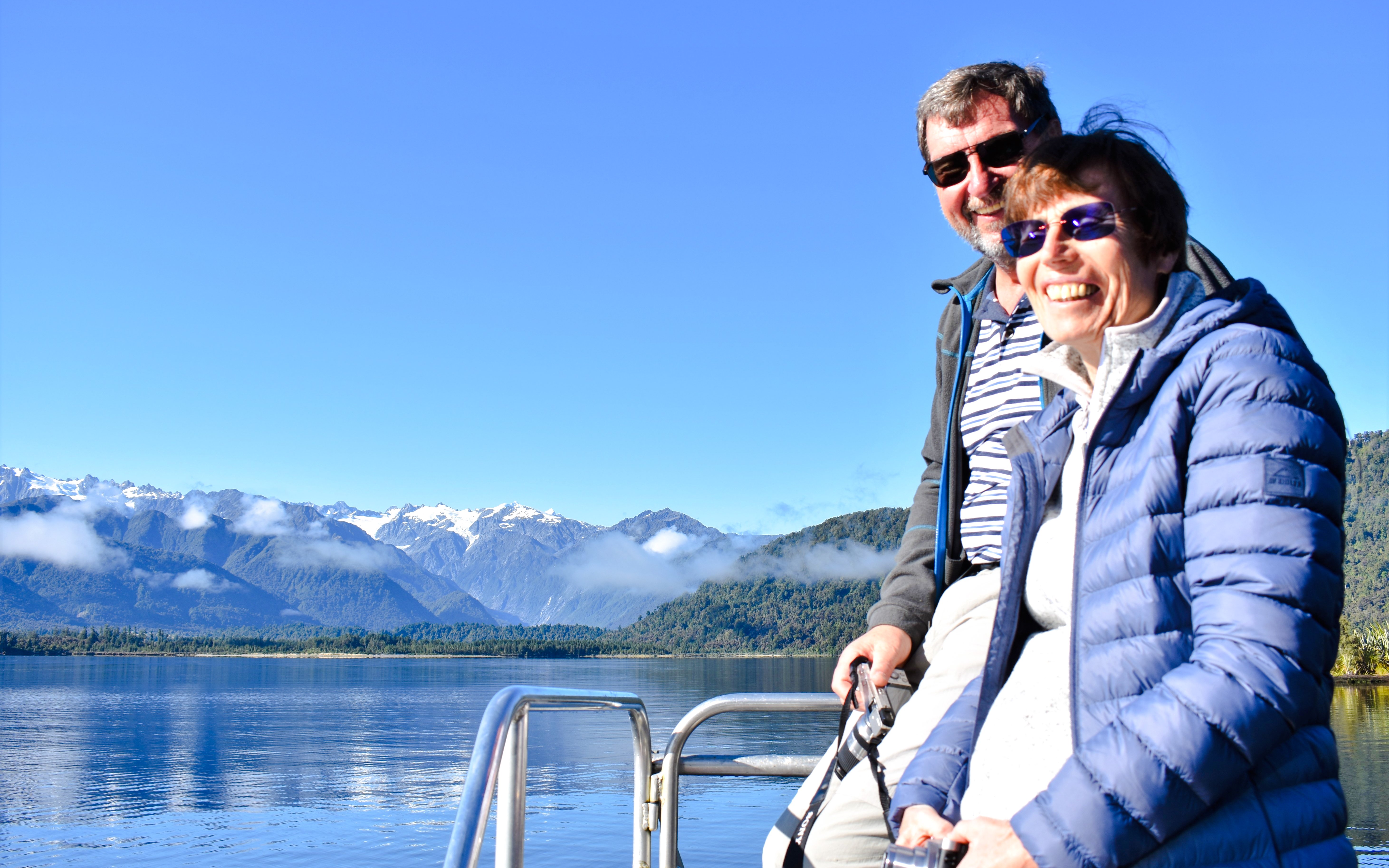 Visitors enjoying a cruise on Lake Mapourika with mountain views.
