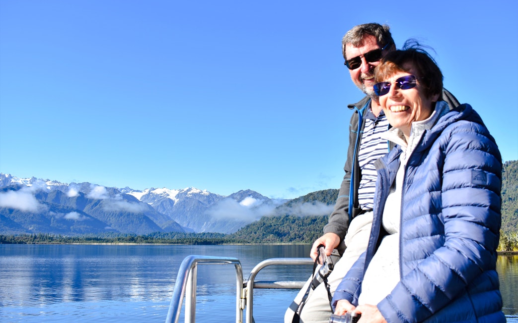 Visitors enjoying a cruise on Lake Mapourika with mountain views.
