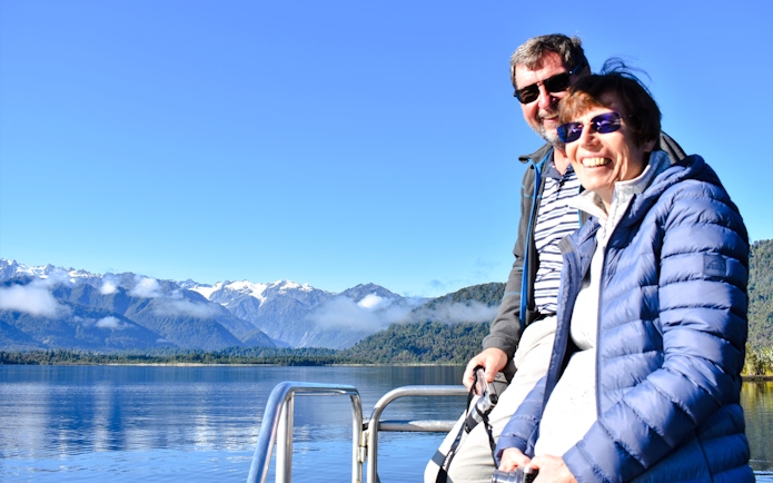 Visitors enjoying a cruise on Lake Mapourika with mountain views.