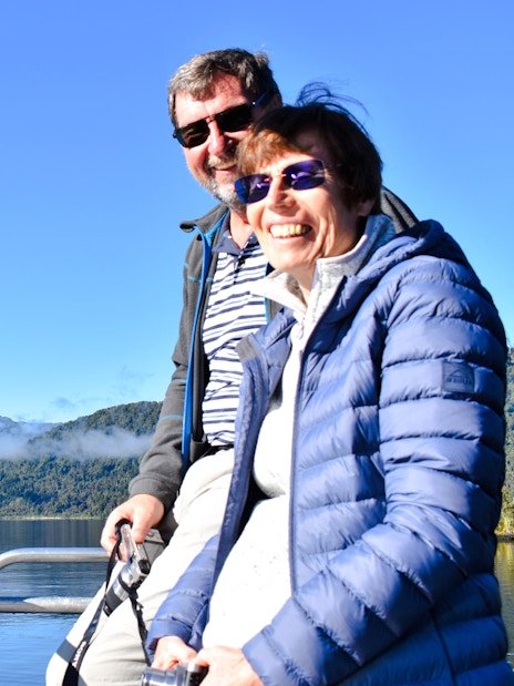Visitors enjoying a cruise on Lake Mapourika with mountain views.