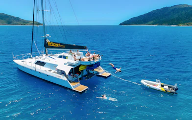 Tourists enjoying a catamaran tour in the Whitsundays, with one diving into the sea.