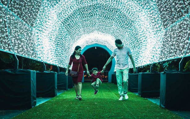 Family walking through illuminated tunnel at Christmas Wonderland, Gardens By The Bay.
