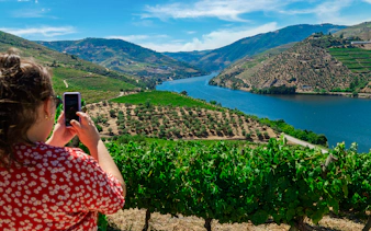 Tourist taking photo of Douro Valley vineyards and river in Portugal.