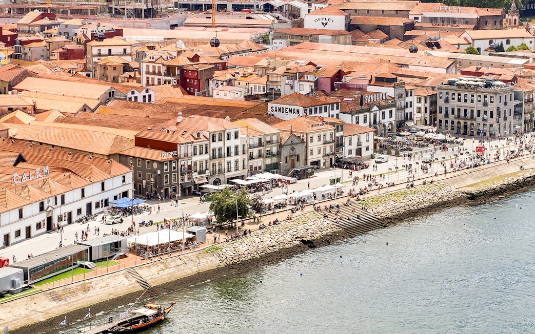 Cálem Cellars in Porto with tourists along the Douro River promenade.