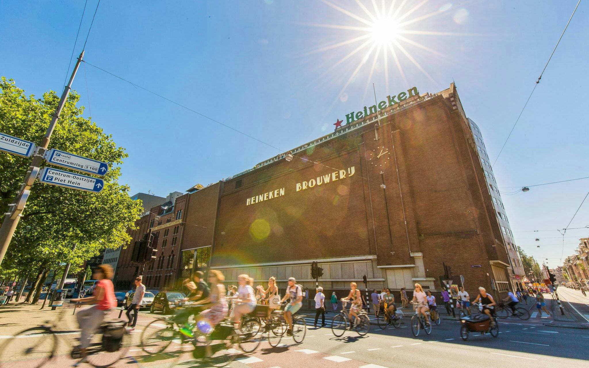 Heineken Brewery building in Amsterdam with cyclists passing by.