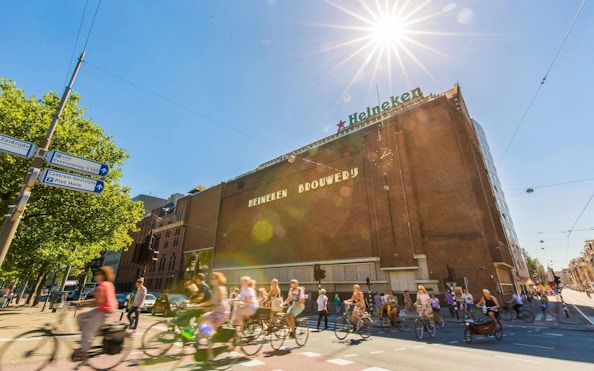 Heineken Brewery building in Amsterdam with cyclists passing by.