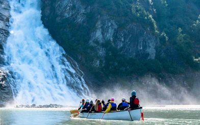 Canoe group paddling near Mendenhall Glacier waterfall in Alaska.