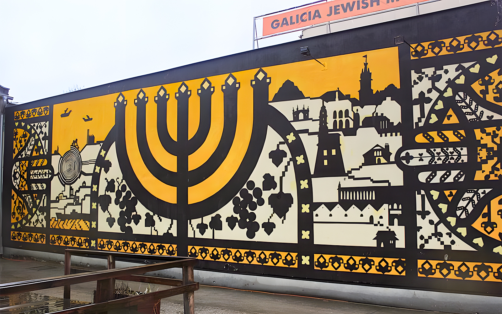 Mural at Galicia Jewish Museum in Kraków featuring a large menorah and cityscape.