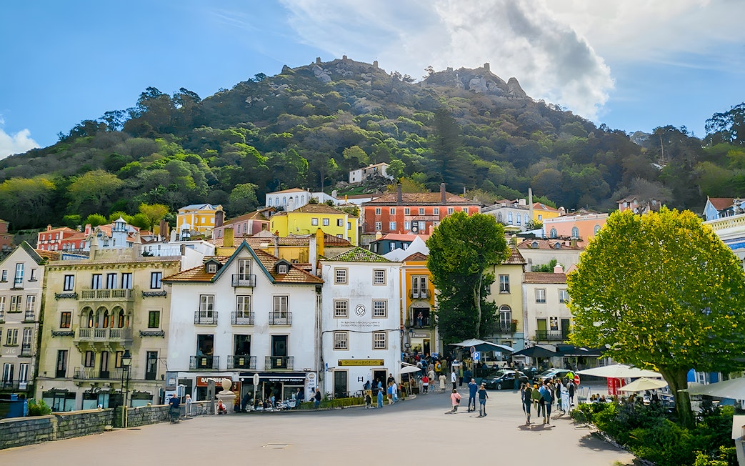 Sintra town square with colorful buildings and Moorish Castle on the hill.