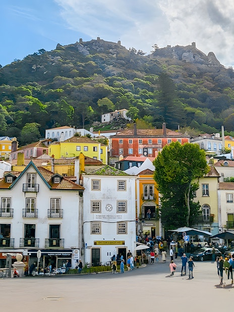 Sintra town square with colorful buildings and Moorish Castle on the hill.