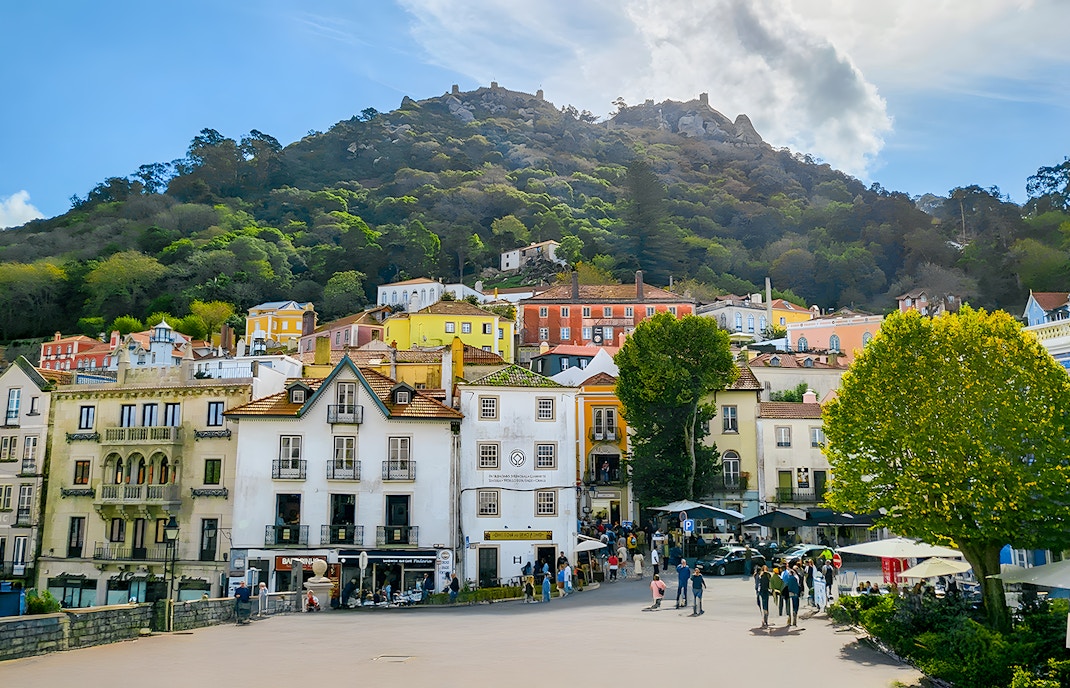 Sintra town square with colorful buildings and Moorish Castle on the hill.