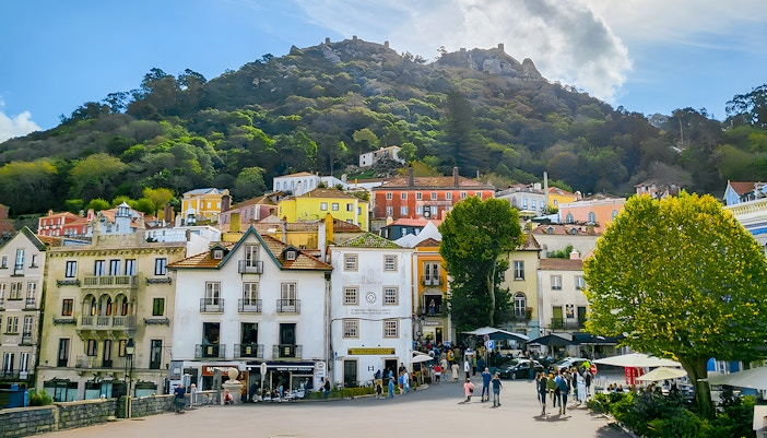 Sintra town square with colorful buildings and Moorish Castle on the hill.