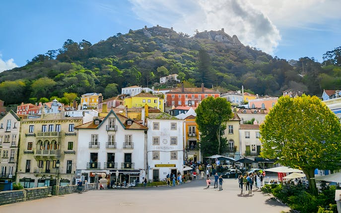 Sintra town square with colorful buildings and Moorish Castle on the hill.